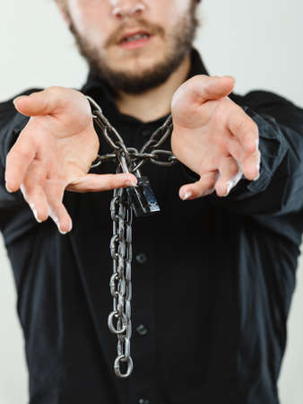 No freedom, social problems concept. Sad man with chained hands, studio shot on light grey backgroundの写真素材