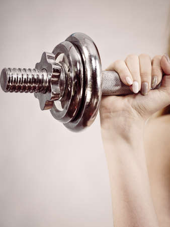Unrecognizable woman working out at home with heavy dumbbell. Training at home, being fit and healthy.の写真素材