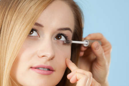 Visage concept. Close up woman getting make up on eyelids. Applying mascara with brush by professional artistの写真素材