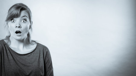 Shock and disbelief concept. Surprised astonished girl with wide open mouth. Amazed female looking...