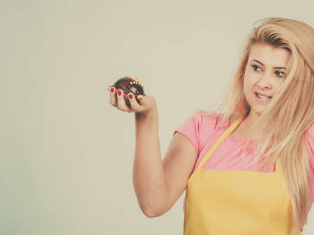 Diet, sweets, food concept. Woman holding delicious chocolate cupcake with peanut frosting about to take biteの写真素材