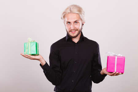 Celebration, special occasion, holidays concept. Trendy young man holding presents pink and green gift boxes in handsの写真素材