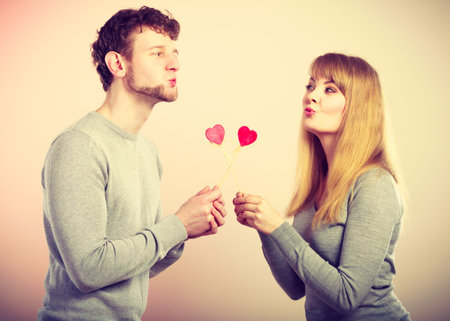 Flirt on date concept. Valentine's Day. Young charming loving pare with love sign symbols little red...