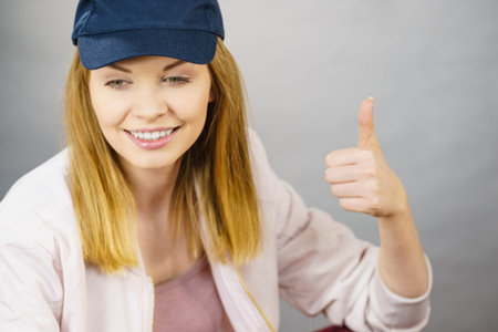 Young sporty teenage looking woman wearing cap and sportswear enjoying workout results. Studio shot...