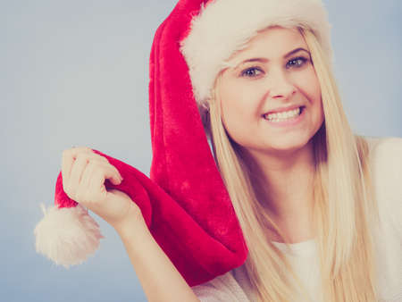 Happy young woman wearing Santa Claus red hat thinking about Christmas gifts and holidays.の写真素材