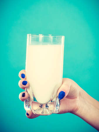 Healthy drinks, good nutrition, dairy products concept. Woman hand holding glass of milkの写真素材
