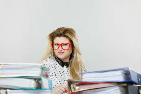 Business woman doing her work sitting working at desk full off documents in binders.の写真素材
