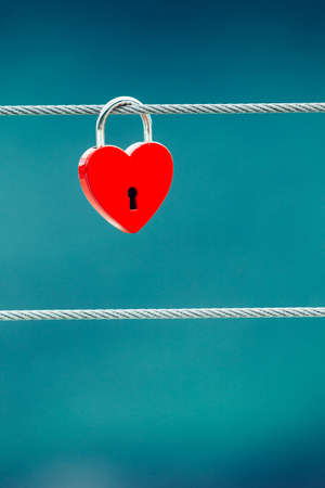 Tourism vacation and travel. Red love heart shaped lock padlock on bridge outdoor, blurred backgroundの写真素材