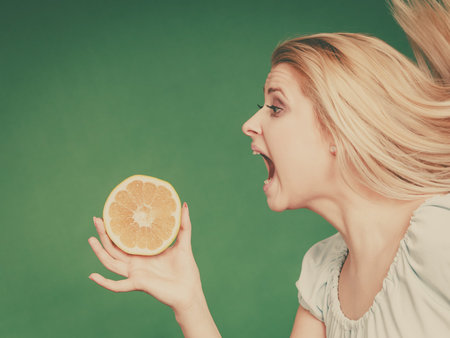 Healthy diet, refreshing food full of vitamins. Woman with open mouth holding sweet delicious citrus...