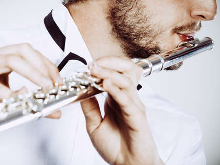 Flute music playing professional male flutist musician performer. Young elegant stylish man with instrument, close upの写真素材