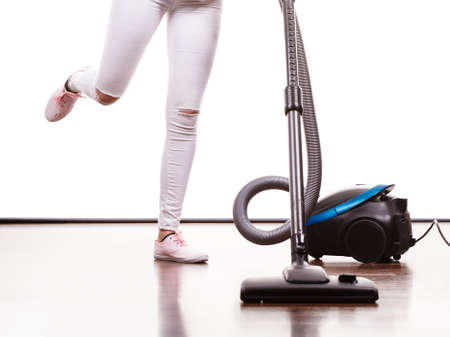 Household cleaning tools and devices, housekeeping duties concept. Woman legs and vacuum cleanerの写真素材