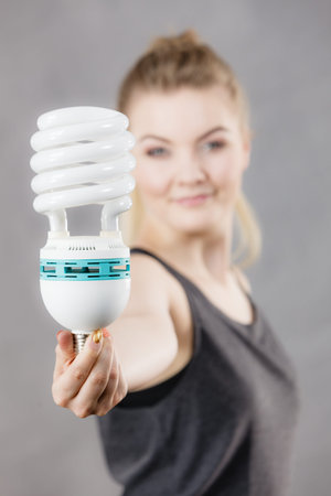 Happy woman holding eco modern light bulb. Innovation technology, power saving concept.