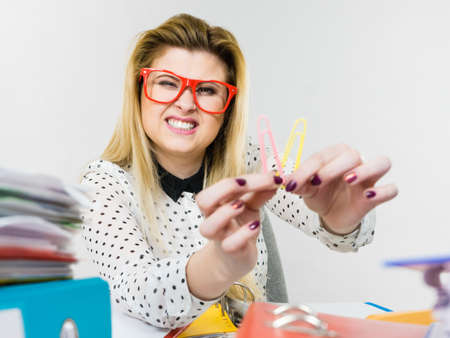 Happy business woman sitting working at desk full off documents in binders showing paper clipsの写真素材