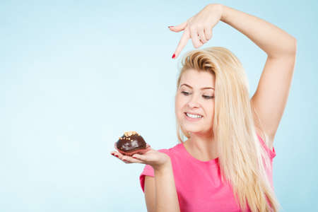 Diet, sweets, food concept. Woman holding delicious chocolate cupcake with peanut frosting about to take biteの写真素材