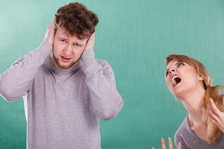 Violence against man. Aggressive woman yelling shouting on scared afraid man. Negative relations in partnership. Expressive young lady screaming.の写真素材
