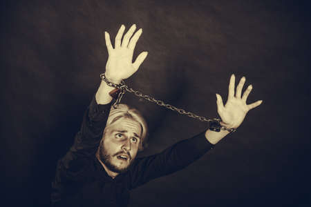 No freedom, social problems concept. Furious man with chained hands, studio shot on dark grunge backgroundの写真素材
