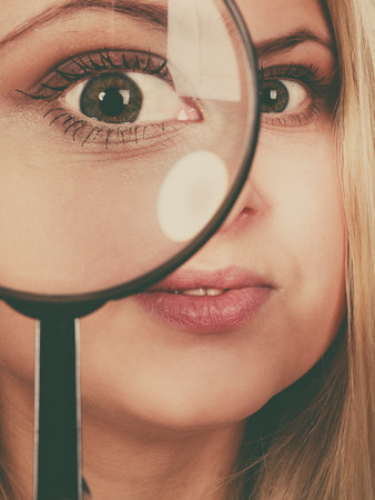 Ophthalmology, spy accessories, eyesight concept. Woman looking through magnifying glass having big...