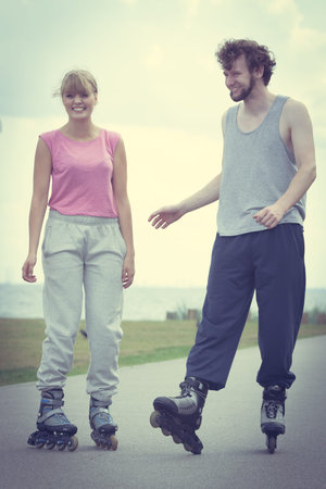 Active lifestyle people and freedom concept. Young fit couple on roller skates riding outdoors on...