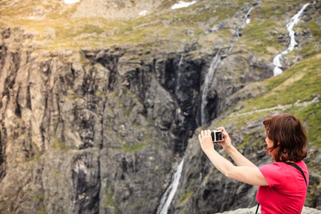 Travel, beauty in nature. Tourist woman looking at mountains, taking picture with camera from...