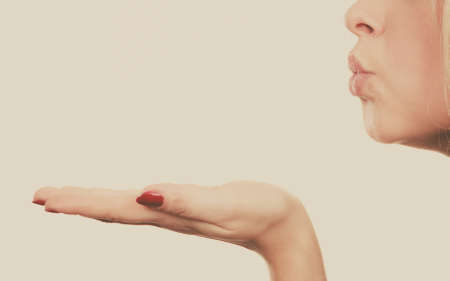Gestures and human reactions concept. Coquet blonde woman sending air kiss on palm hand, profile viewの写真素材