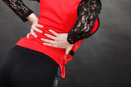 Health problems, strain on joints concept. Closeup of woman in elegant clothes suffers from backacheの写真素材