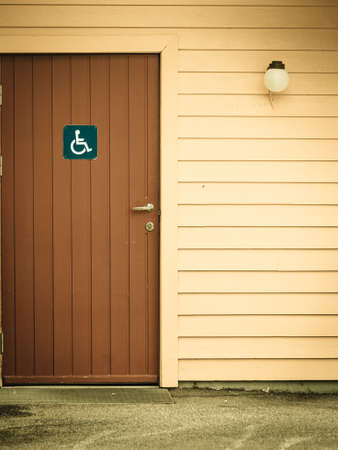 Blue handicapped wheelchair sign on door of public toilet outdoor, WC restroomの写真素材