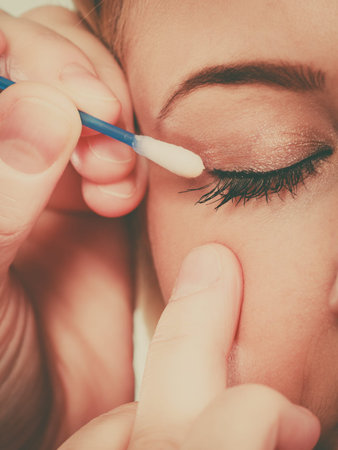 Visage, beauty concept. Closeup portrait of woman face getting her eye makeup done with cotton buds