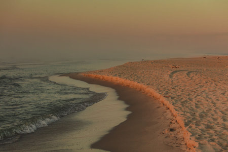 Close up of waving sea water during sunset in orange and gold shades. Dark atmosphereの写真素材