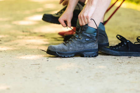 Outdoor leisure holidays trip survival trekking concept. Hikers preparing their footwear. Two tourists checking their boots before further travel.の写真素材
