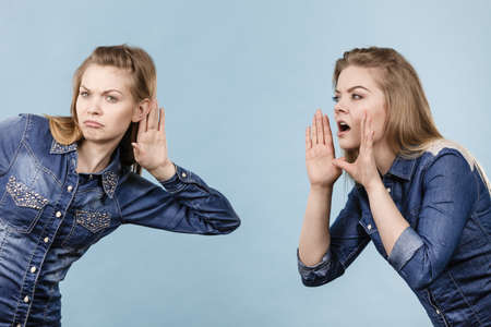 Two women talking gossip, telling tales, girls talk having fun wearing jeans outfit.の写真素材