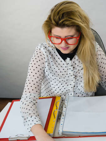 Business woman doing her work sitting working at desk full off documents in binders.の写真素材