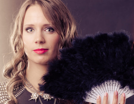 Portrait of beautiful brunette woman with black feather fan in hand
