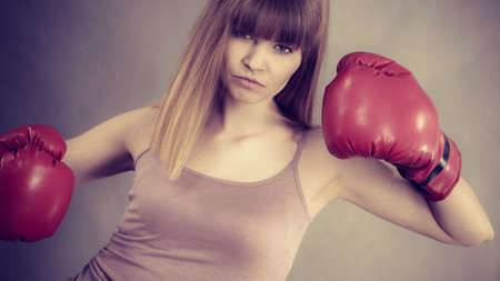 Sporty woman wearing red boxing gloves, fighting. Studio shot on grey, background.の写真素材