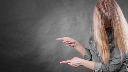 Messages and new information concept. Young blonde casual woman covering her face by hair. Girl showing presenting copy space.の写真素材