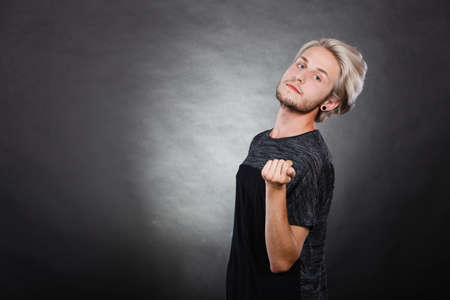 Handsome young fashion model with colored hair highlighted stylish haircut, pierced ear plugの写真素材