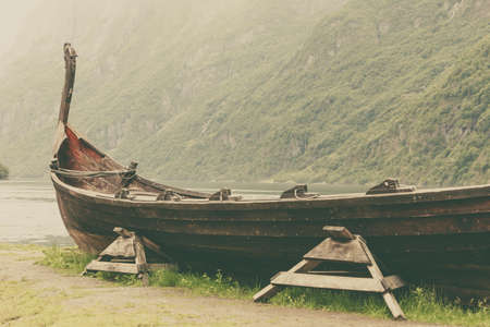 Old wooden viking boat on seashore in norwegian nature. Mountains and fjord Sognefjord. Tourism and traveling conceptの写真素材