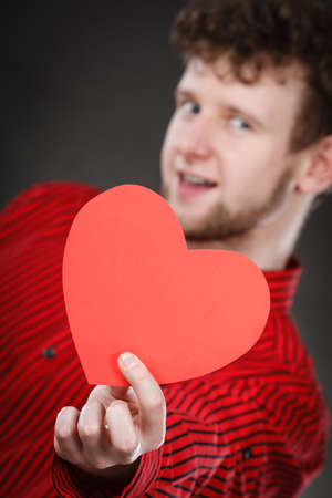 Feelings affection happiness concept. Cheerful man holding heart. Youthful energetic smiling male holding love symbol cutout.の写真素材