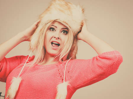 Outfit for cold days ideas, fashion and clothing concept. Attractive smiling blonde woman wearing furry winter hatの写真素材