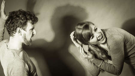 Violence against woman. Aggressive man yelling shouting on scared afraid woman. Negative relations in partnership. Expressive young male beating frightened lady.の写真素材