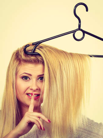 Wardrobe accessories, haircare, hair styling and selling concept. Blonde woman holding hair on clothes hangerの写真素材