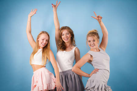 Happy positive female friends having arms raised. Friendship, elegant fashion concept.の写真素材