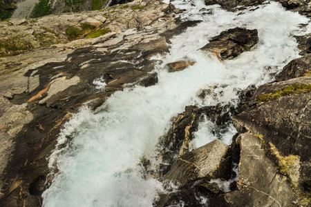 Rocks and stones cliffs with waterfall surrounded with green moss. Background with nature details...