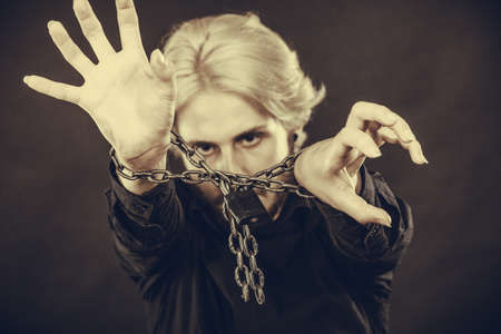 No freedom, social problems concept. Furious man with chained hands, studio shot on dark grunge backgroundの写真素材
