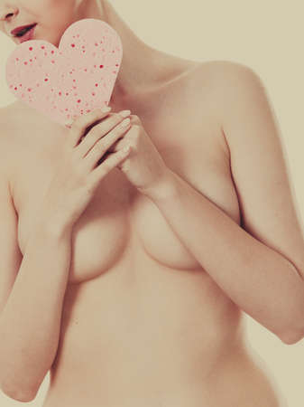 Skincare hygiene medicine and body treatment. Sensual naked woman with beautiful figure perfect skin holding pink heart shaped bath sponge in hands.Toned imageの写真素材