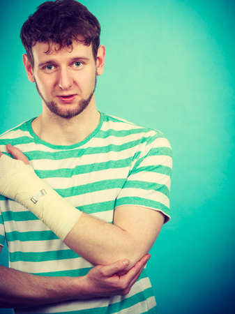 Pain and injury concept. Young man holds bandaged hand. Injured part of body. Medicine and healthcare.の写真素材