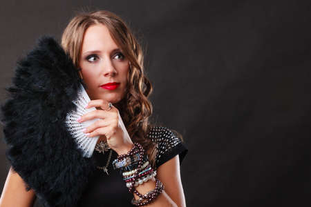 Portrait of beautiful brunette woman with black feather fan in handの写真素材