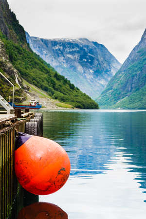 Pier with red buoy ball, norway fjord and mountains in background. Idyllic Scandinaviaの写真素材