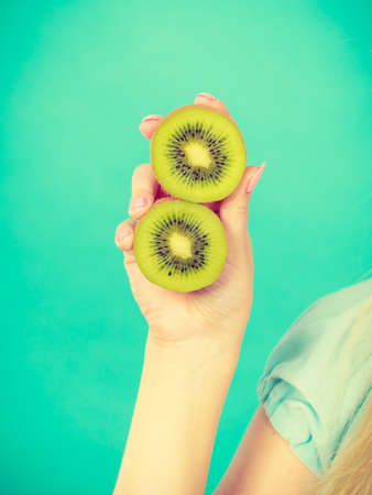 Healthy diet, refreshing food full of vitamins. Woman holding sweet delicious green kiwi fruit.の写真素材