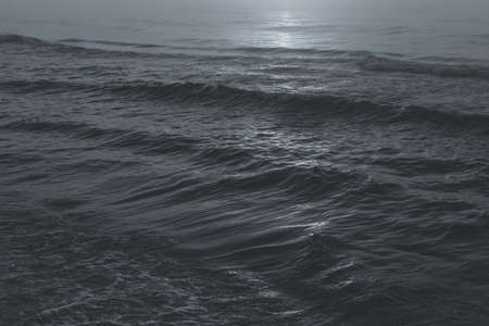 Close up of waving sea water during sunset in black and white shades. Dark atmosphereの写真素材