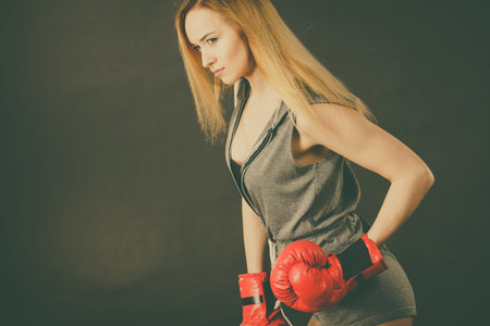 Young sensual woman, blonde attractive girl wearing red punch boxing gloves posing. Sport fitness and power concept.の写真素材